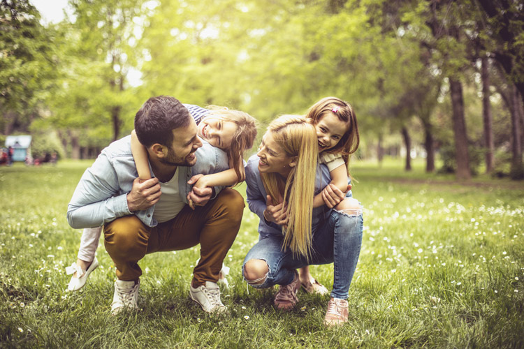 Hier sieht man eine Familie im Gruenen, die sich freut, hier wohnen zu können.